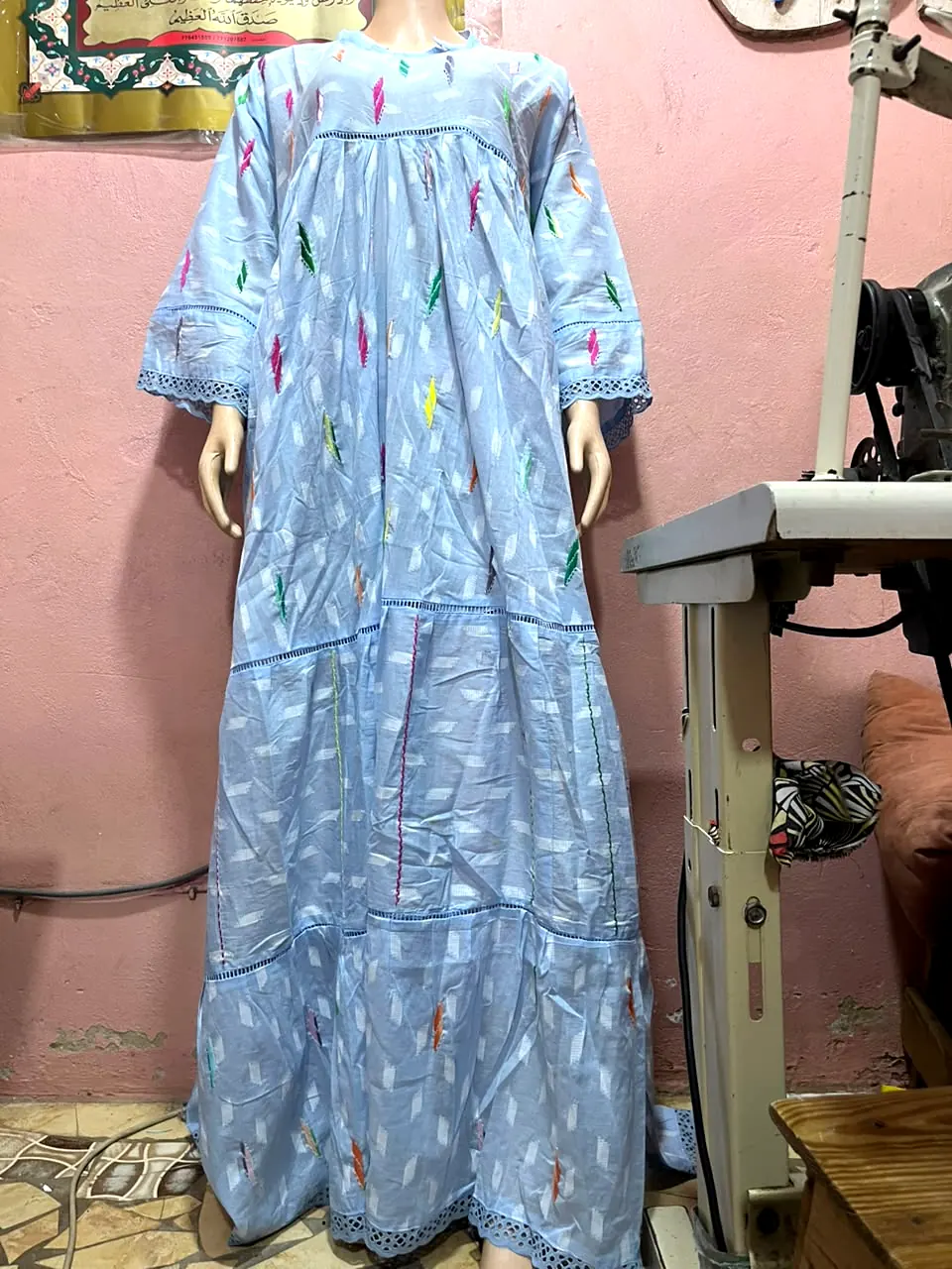 Robe longue bleu ciel ample à étages, petites broderies multicolores, présentée sur mannequin