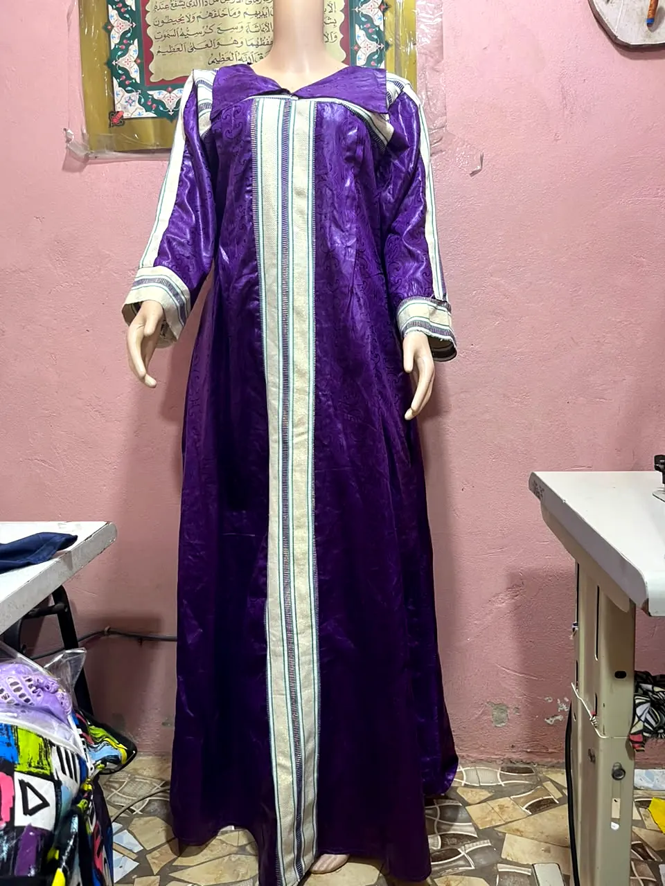 Robe longue violette avec col et galons crème sur le devant et les manches, présentée sur mannequin